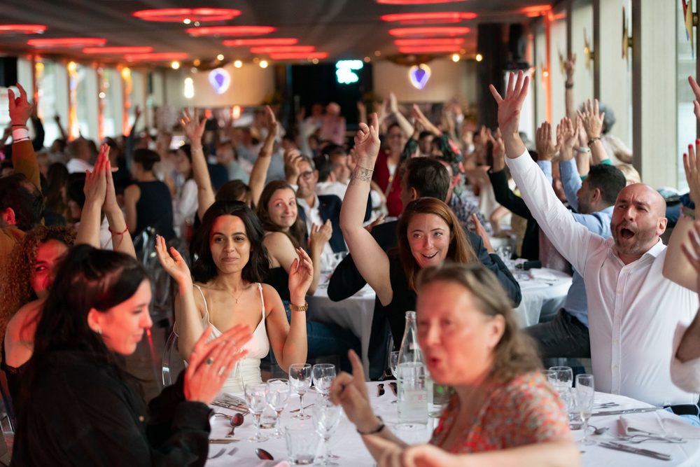 Convives levant les bras et applaudissant lors d'un dîner animé en soirée