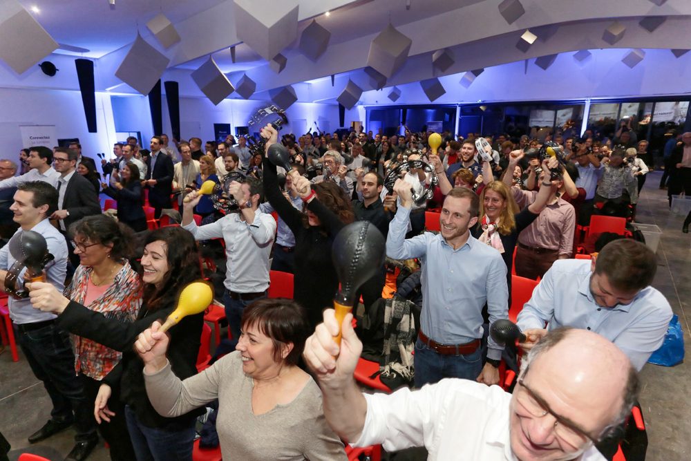 Salle de plénière : les participants brandissent maracas et tambourins lors d'une animation musicale