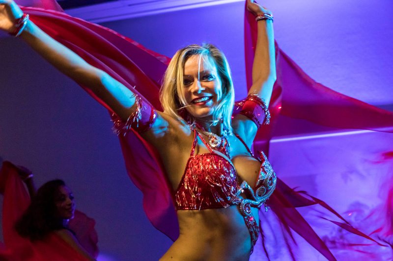 Danseuse orientale en costume rouge faisant virevolter des voiles lors d'une soirée d'entreprise